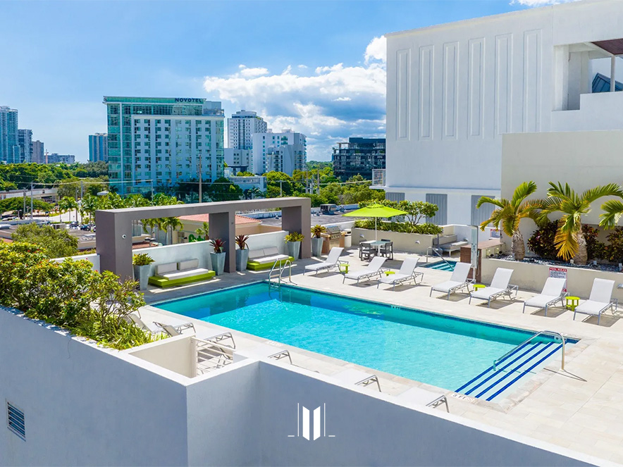Pool and common area with lounge chairs and residential buildings in the background at Brickell First Apartments