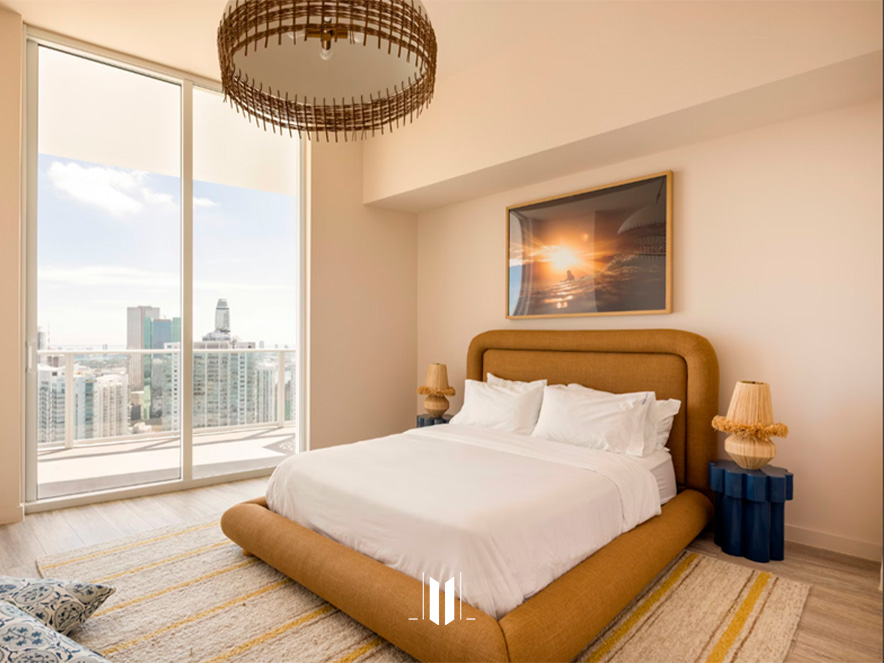 Master bedroom in Flow Brickell with large bed, hanging lamp, and warm decor